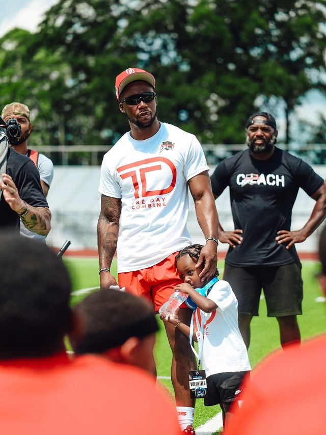 Chester Tre' Rogers in a Tre’ Day tee with young athletes on the field