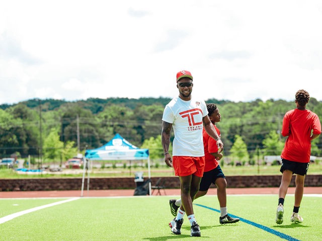 Tre' Rogers walking with young athletes on the field