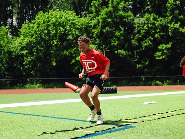 Young athlete running an agility ladder drill in a Tre’ Day jersey