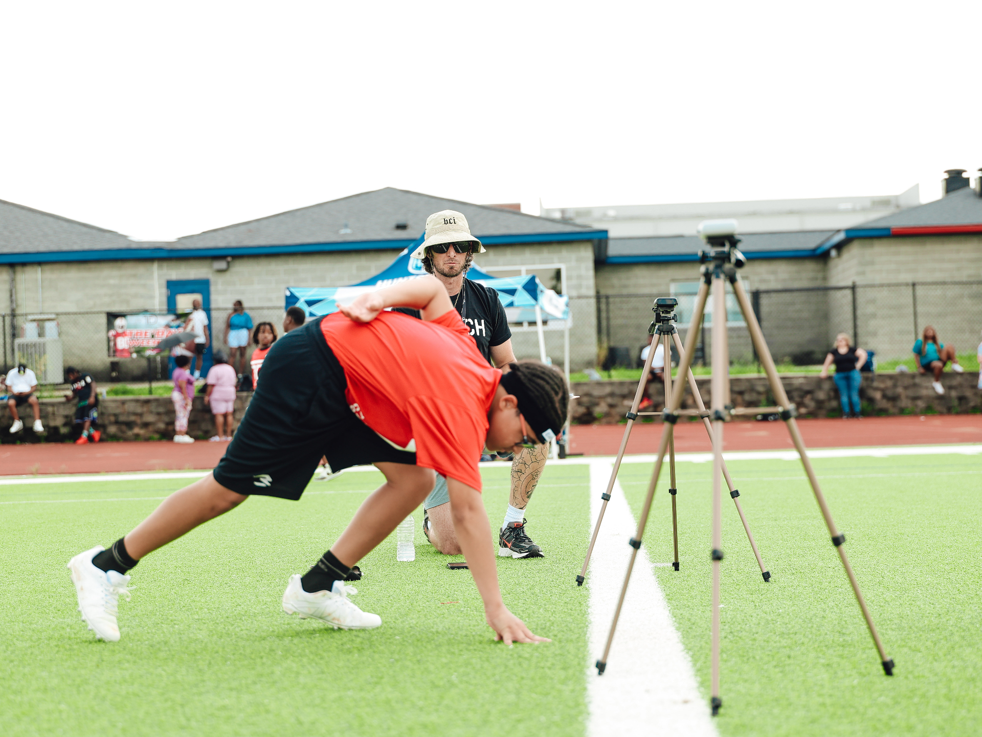 Young athlete stretching on the field with Andy McCloy, Founder of BCI, coaching beside training cones